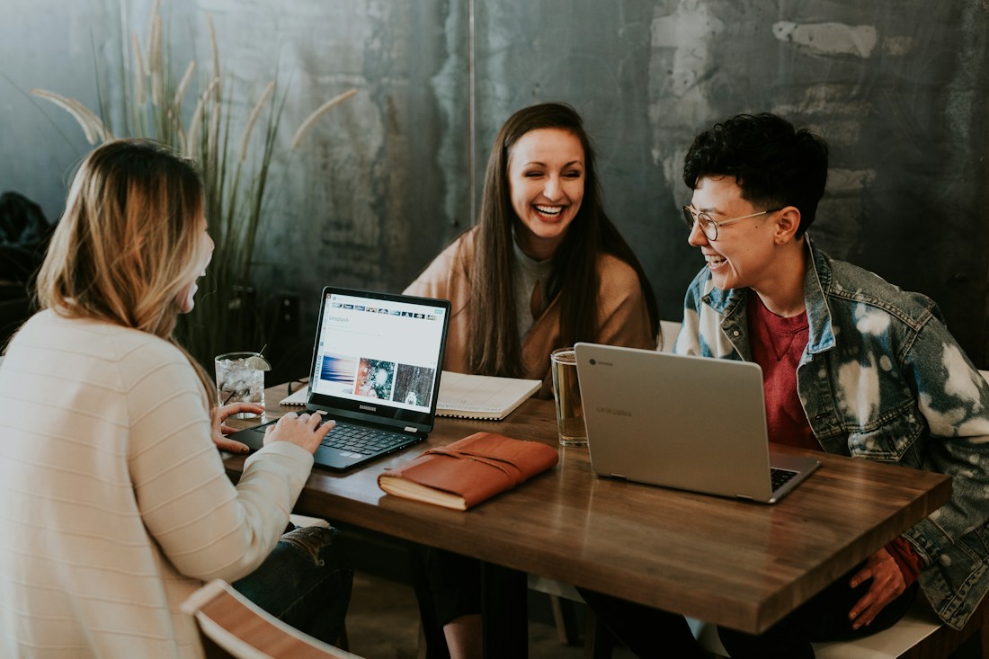 Pessoas trabalhando juntas ao redor de uma mesa com computadores e materiais de projeto